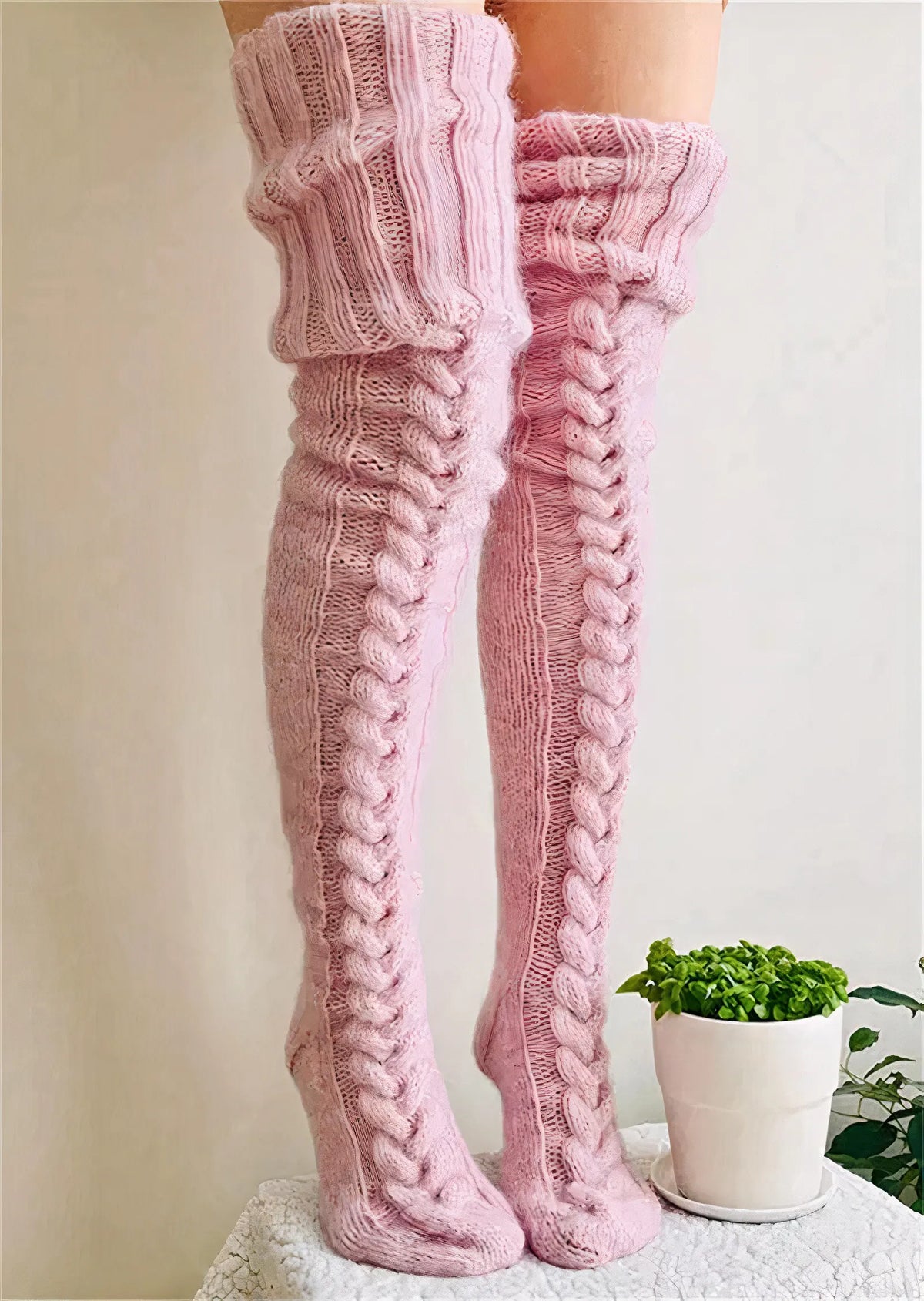 Pink cable knit thigh high socks, full length on a white background