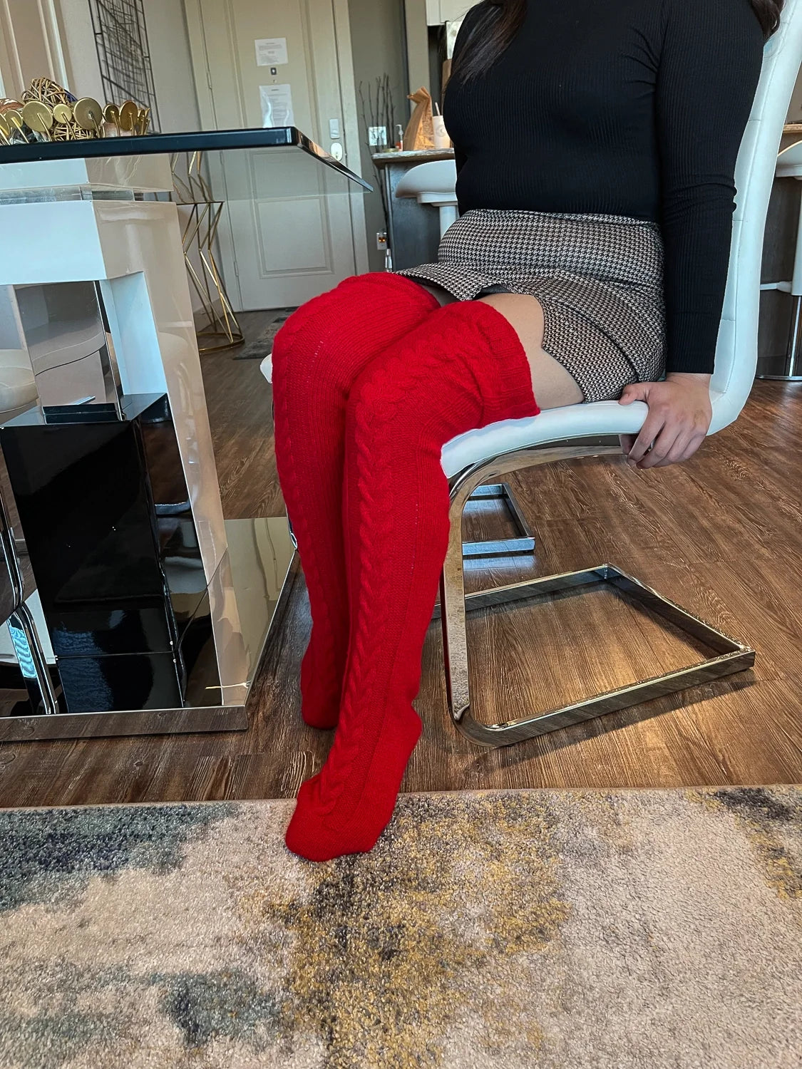 Red cable knit thigh high socks, worn at a dining table with a skirt