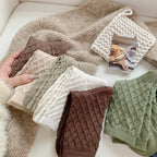 Checked knit crew socks in assorted colours, pairs stacked on a cozy blanket