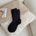 Black checked knit crew socks, close-up on a fluffy blanket