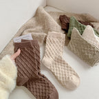 Coffee, milky white and green checked knit crew socks, pairs on a cozy blanket