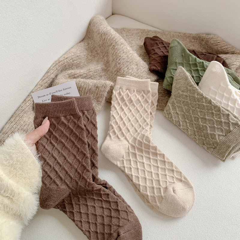 Coffee, milky white and green checked knit crew socks, pairs on a cozy blanket