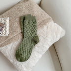 Green checked knit crew socks, close-up on a fluffy blanket