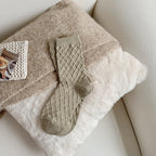 Light gray-green checked knit crew socks, on a fluffy blanket