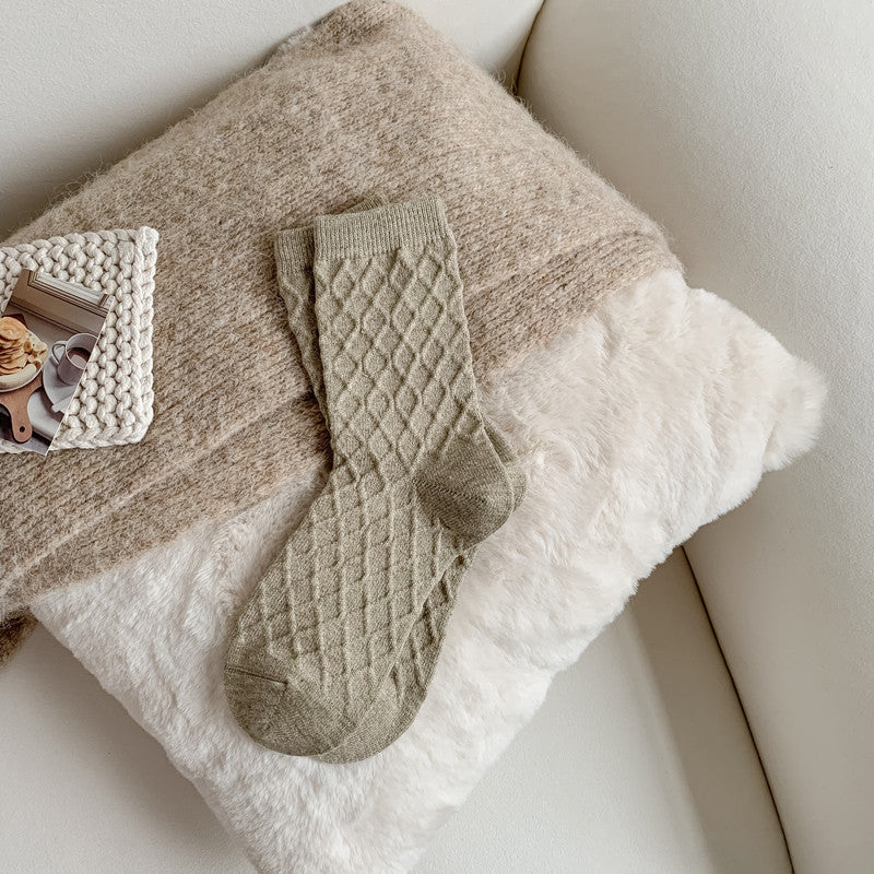 Light gray-green checked knit crew socks, on a fluffy blanket