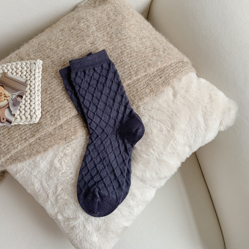 Navy blue checked knit crew socks, close-up on a fluffy blanket