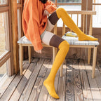 Yellow cotton over the knee socks, worn with an orange sweater on a bench