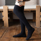 Black cotton thigh high socks, worn standing, side view of the ribbed knit