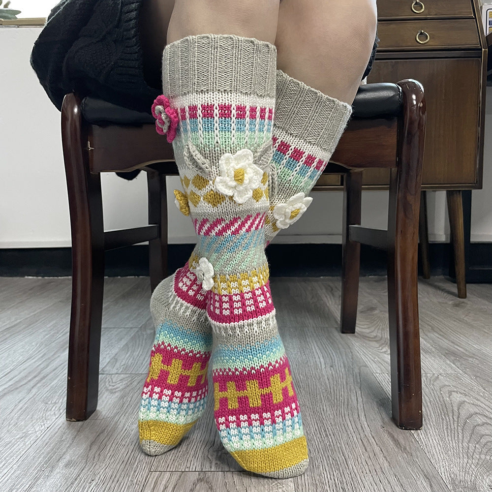 Gray and red floral jacquard knee high socks, worn while seated, front view