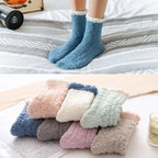 Pastel fuzzy thermal socks, blue pair worn in bed, with a stack of colours