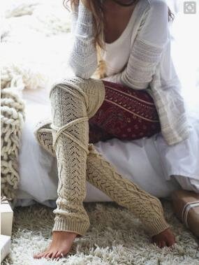 Beige long cable knit leg warmers, worn sitting on a fluffy rug