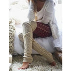Beige long cable knit leg warmers, worn sitting, scrunched at the ankle