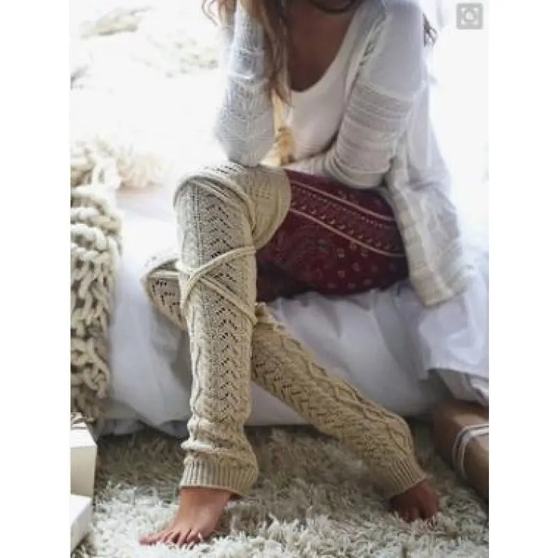 Beige long cable knit leg warmers, worn sitting, scrunched at the ankle