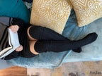 Black long knit over the knee socks, lounging on a sofa with a book