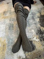 Dark gray long knit over the knee socks, crossed legs on a rug