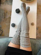 Gray long knit over the knee socks, legs resting on a coffee table