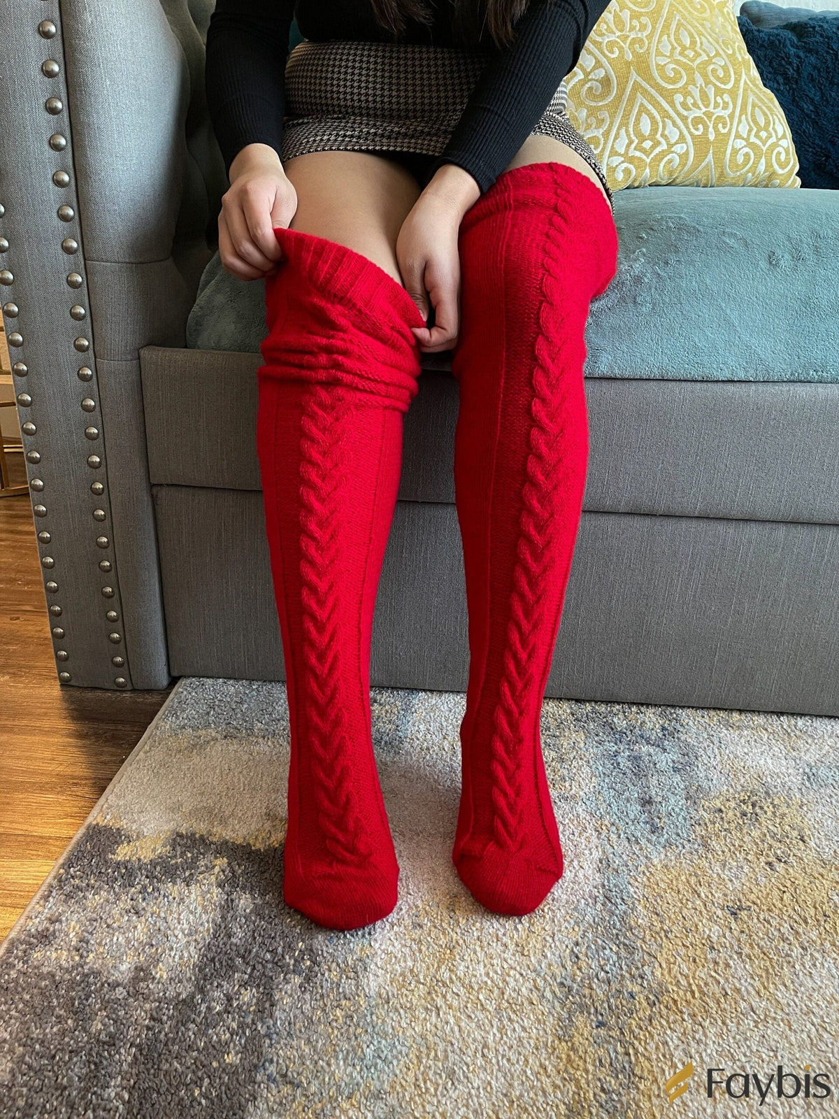Red long knit over the knee socks, pulled up while sitting on a sofa