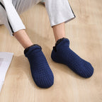 Navy blue non-slip slipper socks, worn walking on a wooden floor