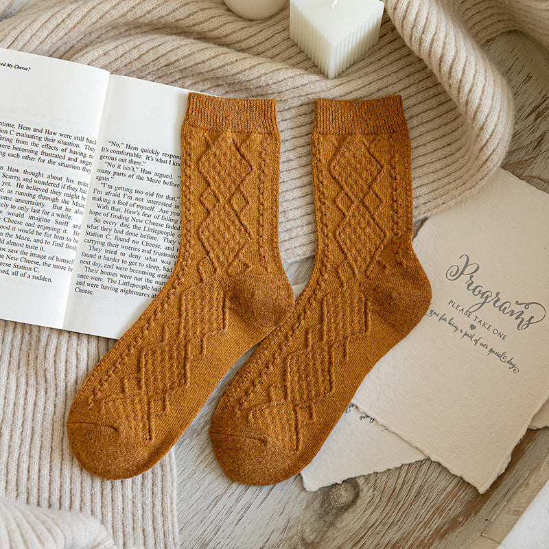 Yellow ribbed wool blend crew socks, pair laid on an open book
