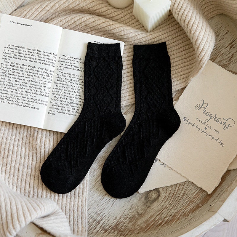 Black soft knit crew socks, pair laid on an open book