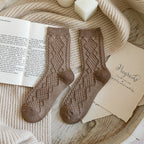 Light coffee soft knit crew socks, pair laid on an open book