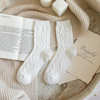 White soft knit crew socks, pair laid on an open book