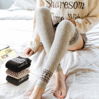 Light gray wool blend thigh high socks, worn relaxing on a bed